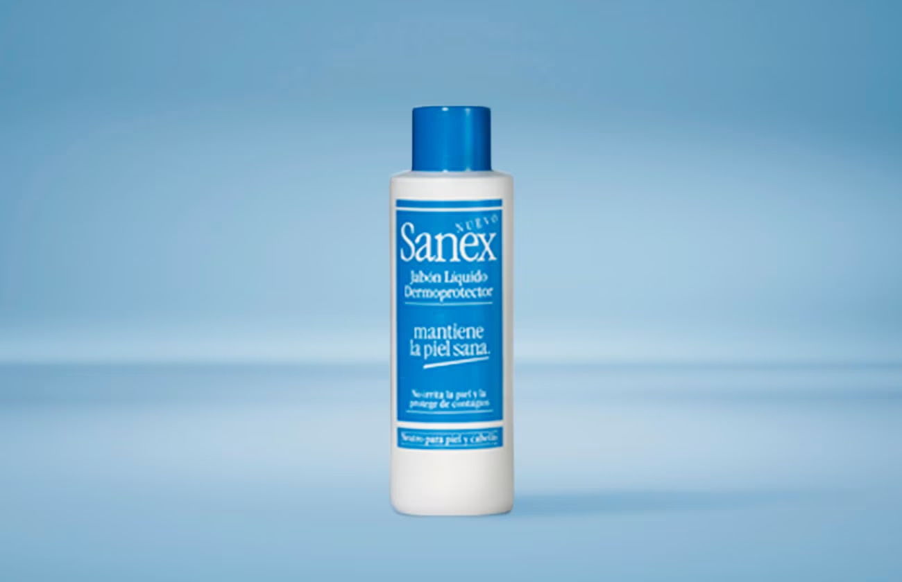 Een fles Sanex vloeibare dermoprotector zeep, met een blauwe dop, tegen een lichtblauwe achtergrond.