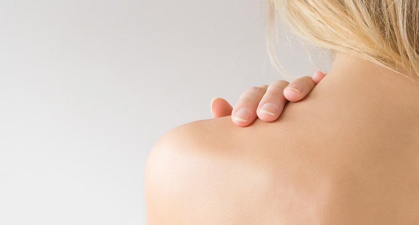 Woman touching the skin on her shoulder