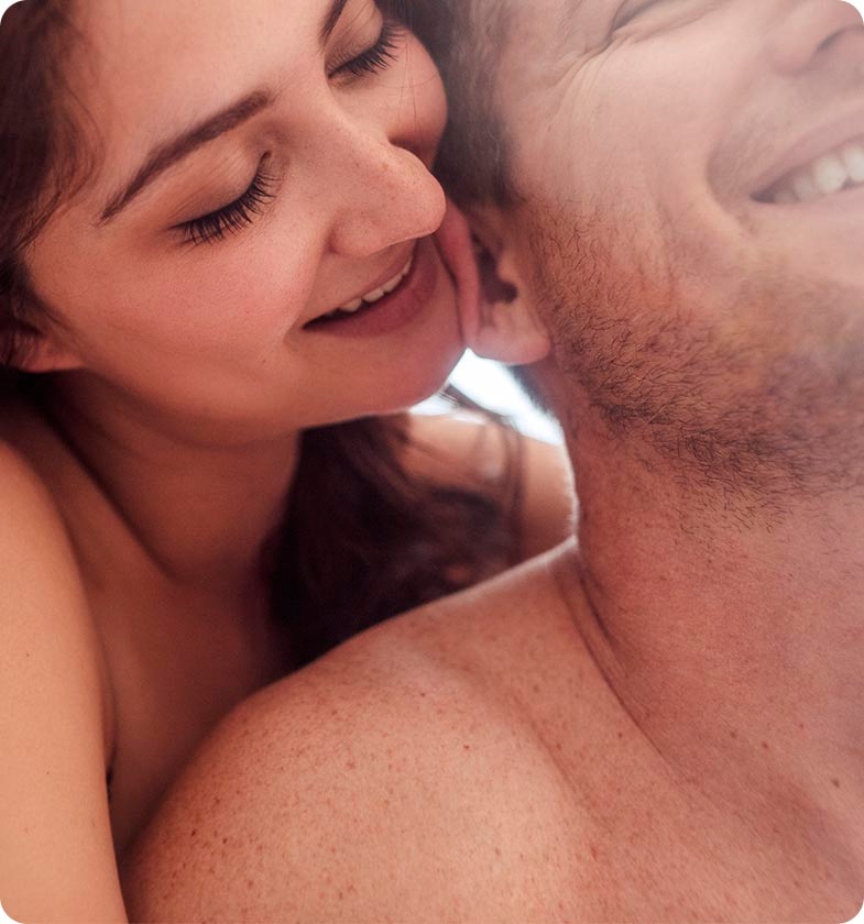 Man and Woman both smilinng, woman is touching the man's ear with her face, while hugging him from behind Man and Woman both smilinng, woman is touching the man's ear with her face, while hugging him from behind