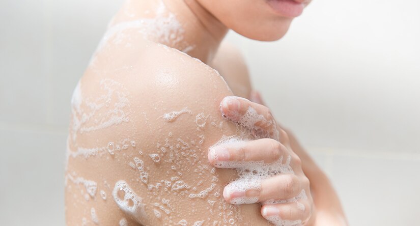 A woman applying shower gel to her skin