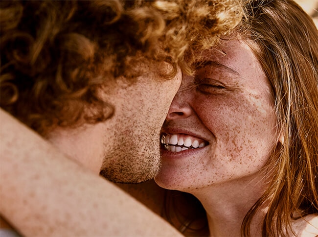 Man and woman smile, holding and hugging each other 