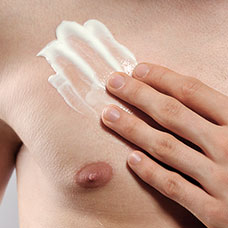 Hand holding her breast with lotion covered on top