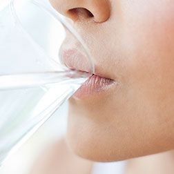 Woman drinking water, from a glass, touching her lips