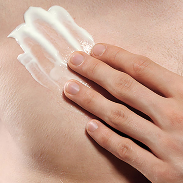 Woman's hand holding her breast with lotion covered on top